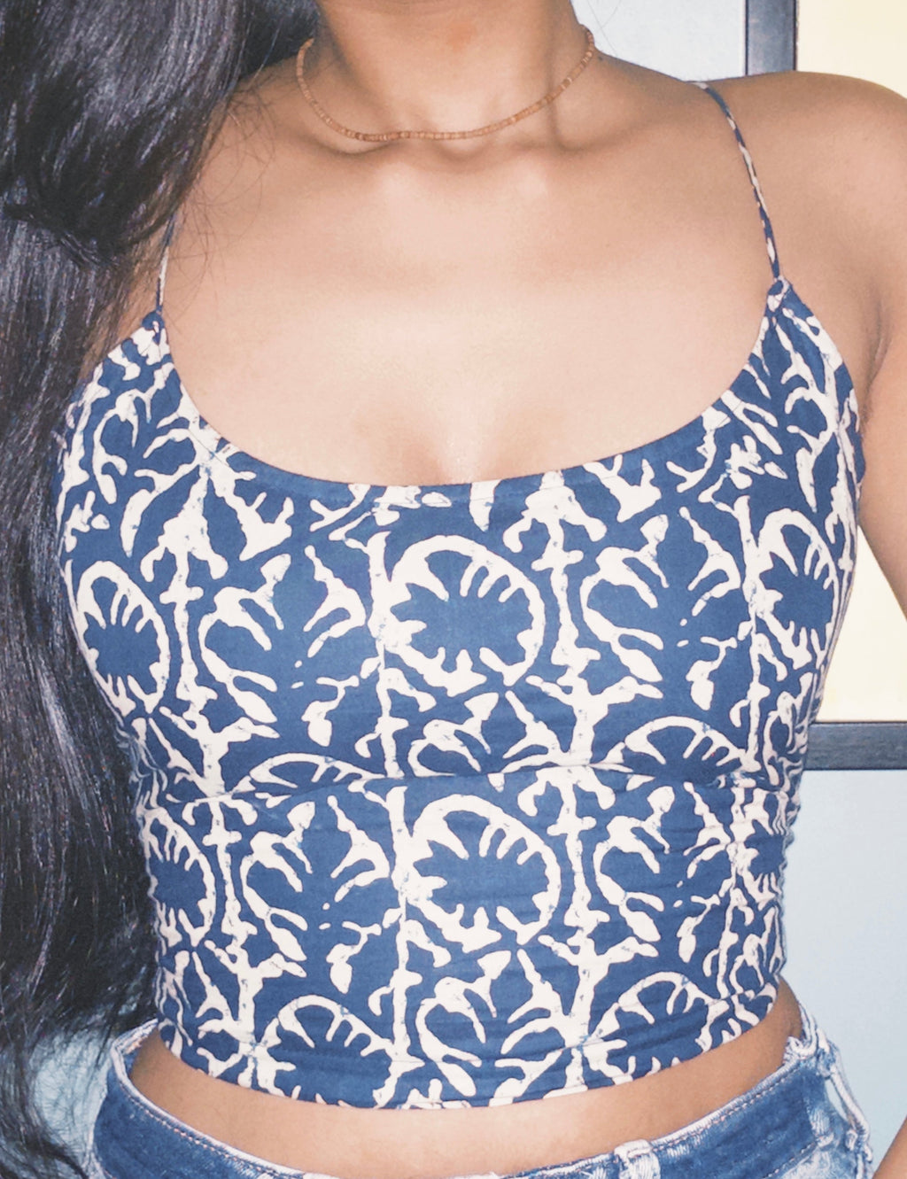 Blue and white patterned crop top worn by a person. A woman wearing Surzaa  Dabu backless blue and white patterned corset top with a lace-up back. 