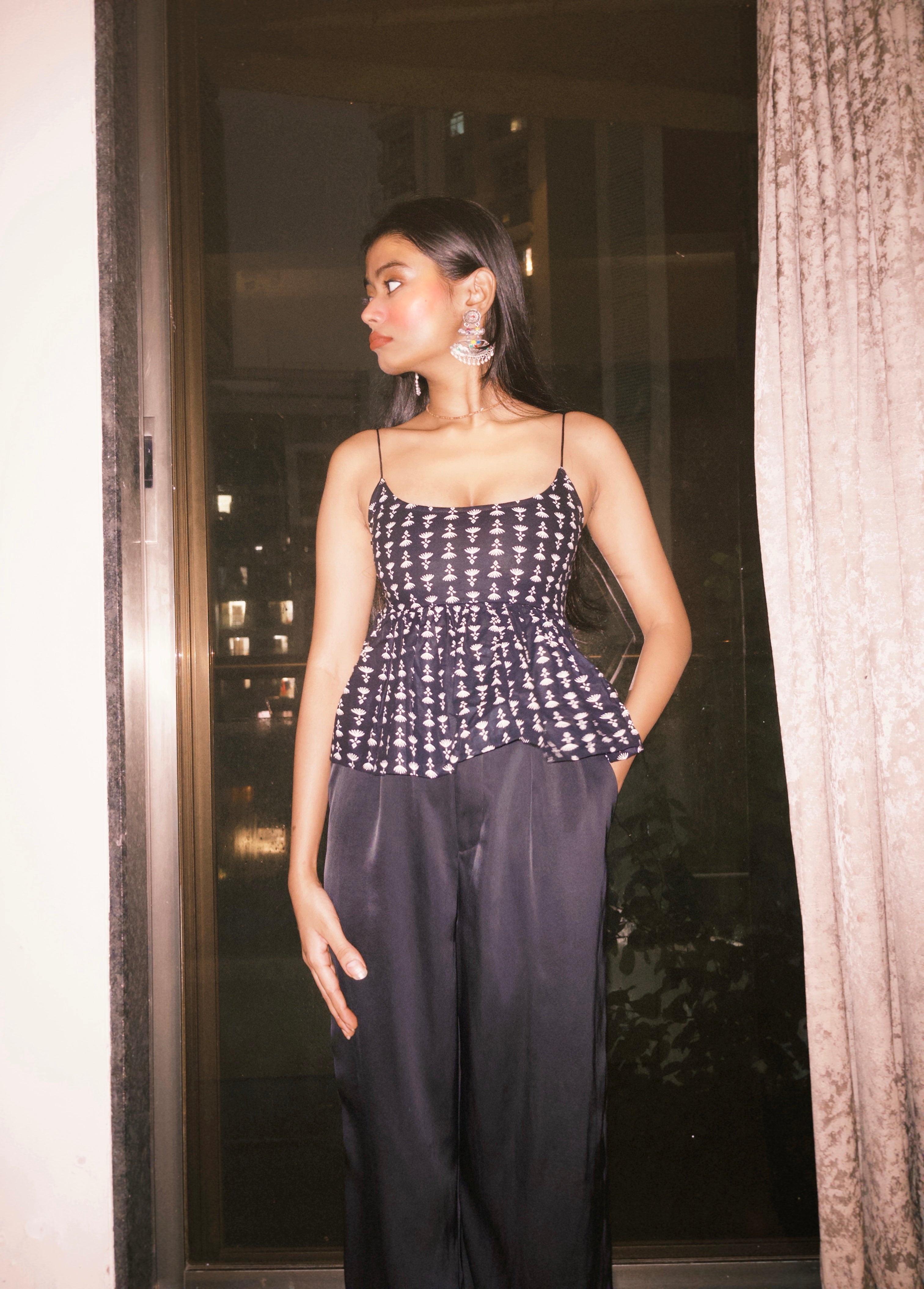 Woman wearing a black and white patterned top and dark pans.