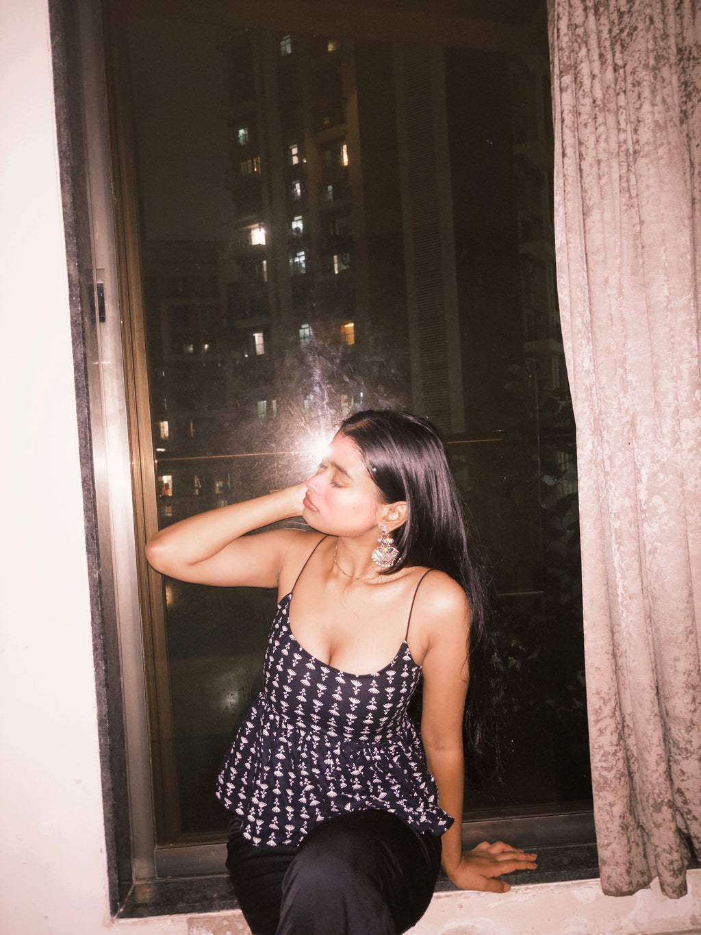 A woman wearing a dark-colored backless top with a white pattern and a criss-cross lace-up back detail.