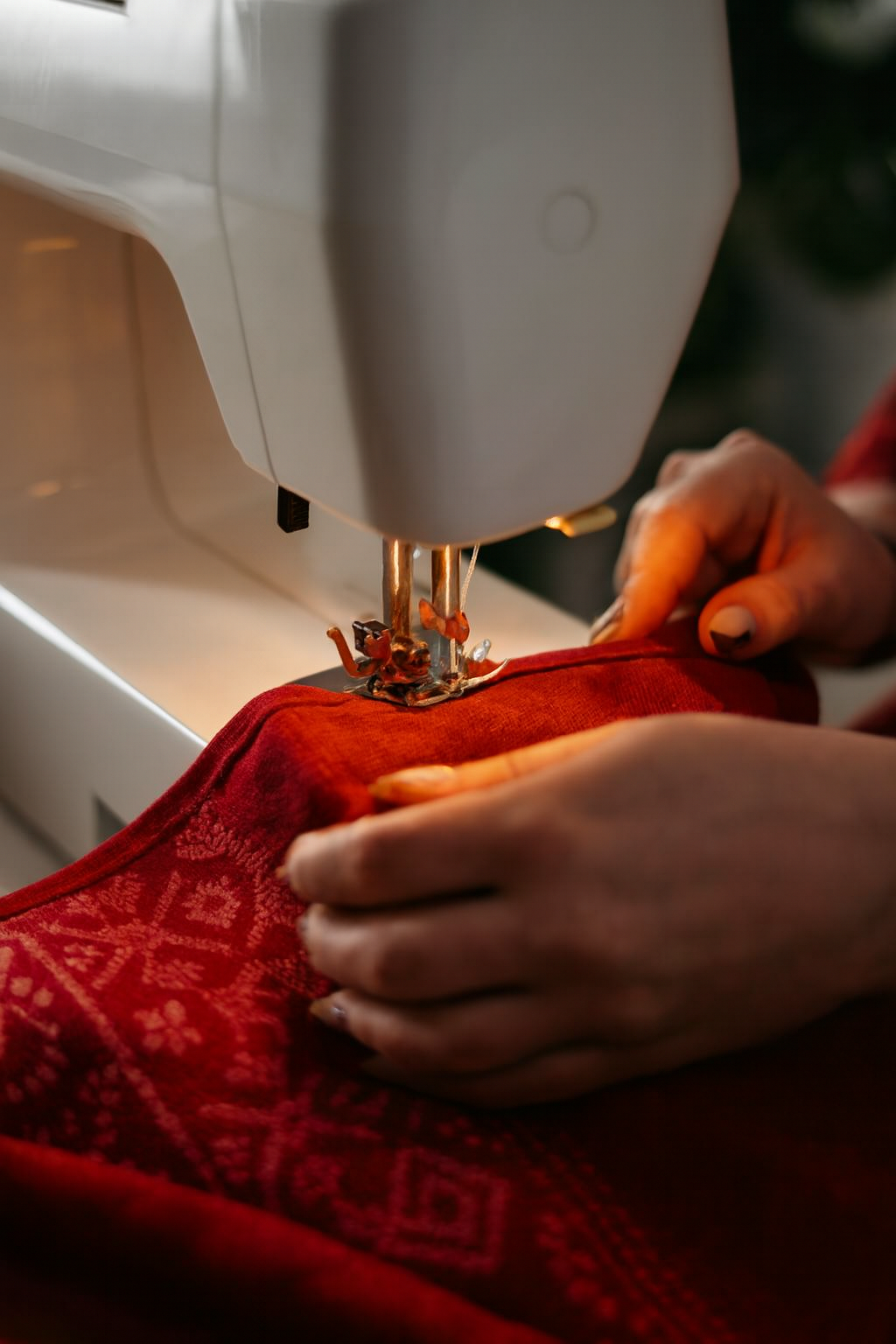 Person using a sewing machine on red fabric with a blurred background